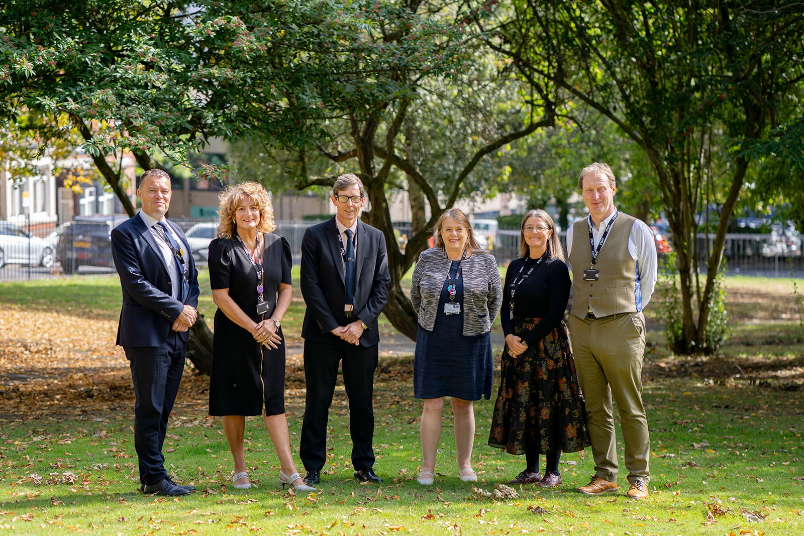 Luminate Education Group's Executive Leadership Team standing together outside on grass, in sunshine